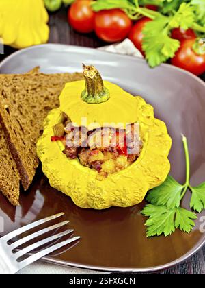 Squash gelb gefüllt mit Fleisch, Tomaten und Paprika, Brot in einen braunen, Tomaten, Petersilie und Gabel auf dem Hintergrund der Holzbretter Stockfoto