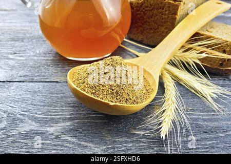 Malz in einem Löffel, Brot, kwass in einem Krug und ährchen auf dem Hintergrund der Holzplatte Stockfoto