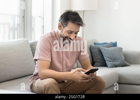Lächelnder Einzelmann chatte online mit E-Dating-Anwendung auf dem Smartphone Stockfoto