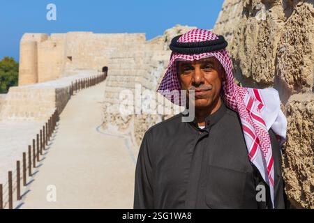 Bahrain-Mann in traditioneller Kleidung im Qal'at al-Bahrain, auch bekannt als Bahrain Fort oder Portugiesisches Fort, ein UNESCO-Weltkulturerbe in Manama, Bahrain Stockfoto