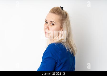 Blonde Frau im blauen Pyjama dreht ihren Kopf mit einem seltsamen Blick Stockfoto