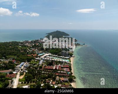 Küstendorf umgeben von Grün mit Hügeln im Hintergrund und türkisfarbenem Meer entlang der Küste. Ko Pha Ngan, Thailand. Stockfoto