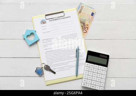 Leeres Haus Mietvertrag mit Schlüssel, Geld und Rechner auf weißem hölzernem Hintergrund Stockfoto