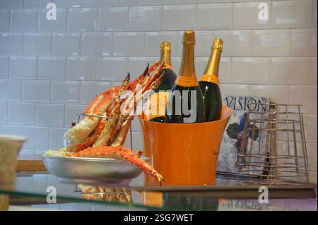In Amsterdam sitzen zwei Champagnerflaschen und eine Schüssel mit gekochten Krabbenbeinen einladend auf einer Theke. Die glitzernden Krabbenbeine deuten auf eine feierliche Mahlzeit hin Stockfoto