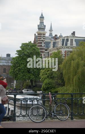 Amsterdams historischer Kanal, gesäumt von großer Architektur, ist eine friedliche Szene. Im Hintergrund steht das Museum Villa Alsberg, dessen Reflexion schimmert Stockfoto