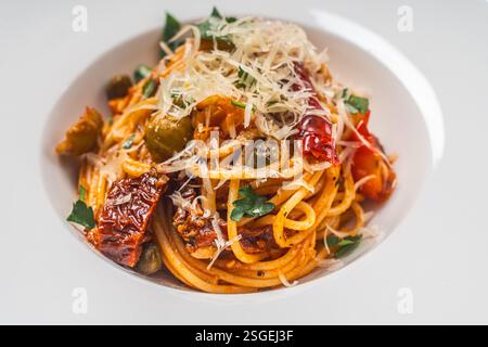 Spaghetti oder Putanessa-Pasta nach traditionellem italienischem Rezept mit Sardellen, Oliven, Kapern und Tomaten auf einem weißen Teller. Nahaufnahme. Leerzeichen f Stockfoto