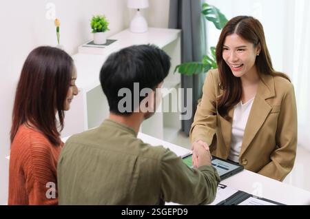 Asiatische Paare handschütteln und unterzeichnen Vertragsfinanzdokumente unter Anleitung eines Beraters zu Hause, Zusammenarbeit und durchdachte Planung für Finanzen Stockfoto