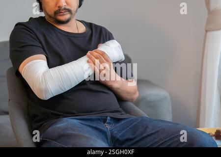 Mann mit Arm und Hand in medizinischen Verband gewickelt zu Hause. Erste Hilfe, Behandlung nach Unfallverletzungen. Kopierbereich Stockfoto