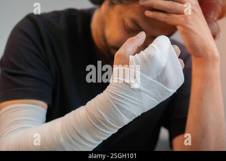 Ein Mann mittleren Alters, der ein schwarzes Hemd trug, verletzte sich die Hand und fühlte sich besorgt und gestresst. Selektiver Fokus. Stockfoto