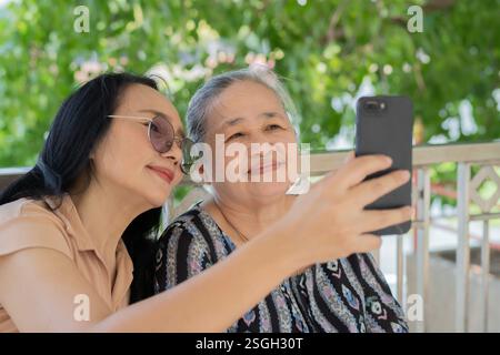 Asiatische Seniorinnen und Töchter, die Fotos mit dem Handy machen. Selektiver Fokus. Stockfoto