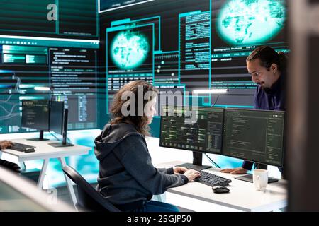 Hacker aus der Regierung, die fortschrittliche Software zum Schutz vor Cyberbedrohungen einsetzen, arbeiten im Team. Spezialisten für Cybersicherheit, Daten- und Netzwerkschutz vereinen Kräfte in High-Tech-Büros. Stockfoto