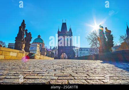 Der flache Blick auf die Karlsbrücke mit alten Steinpflastern, geschnitzten Steinstatuen und dem Altstadtbrückenturm im Hintergrund, Prag, Tschechien Stockfoto