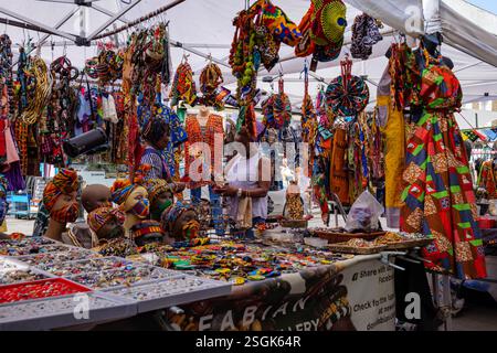 London - 06 17 2022: Mehrfarbiger Karibik-Kleiderstand, bei dem der Kunde Bargeld auf der Portobello Rd. Zahlt Stockfoto