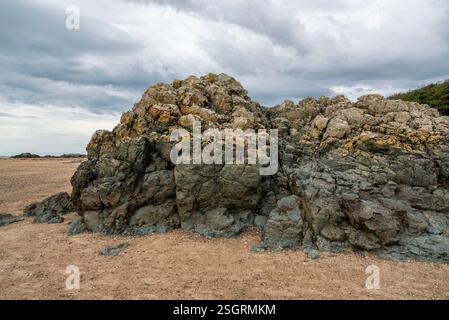 Felsen bilden sich am Newborough Beach in Anglesey, Nordwales. Stockfoto