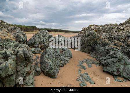 Felsen bilden sich am Newborough Beach in Anglesey, Nordwales. Stockfoto