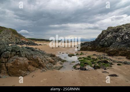 Felsen bilden sich am Newborough Beach in Anglesey, Nordwales. Stockfoto