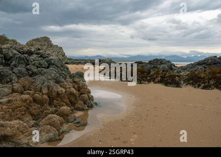 Felsen bilden sich am Newborough Beach in Anglesey, Nordwales. Stockfoto