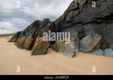 Felsen bilden sich am Newborough Beach in Anglesey, Nordwales. Stockfoto