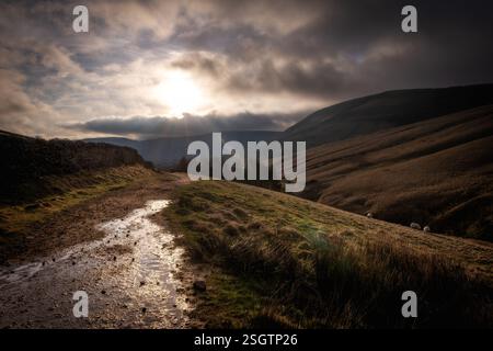 Die niedrige Wintersonne bricht über den Wolken auf, die den pennine Way im Edale Valley Peak District Nationalpark Derbyshire, Großbritannien, erleuchten. Stockfoto