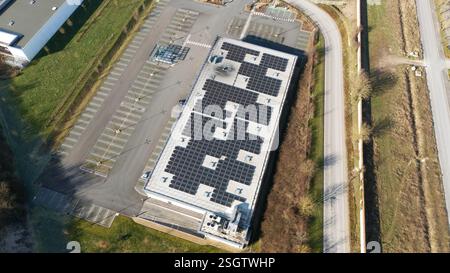 Top-Down-Luftaufnahme eines großen Gebäudes in Epernay, Frankreich, mit Solarpaneelen auf dem Dach, umgeben von Parkplätzen und Grün. Stockfoto