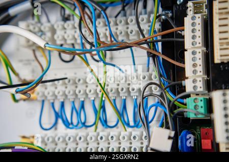Farbenfrohe Drähte und Komponenten, die mit dem Anschlussblock im Verteilerkasten verbunden sind. Elektrische Leiterplatte mit Verkabelung und Anschlüssen Stockfoto