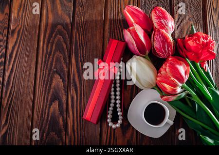 Valentinstag Morgenkaffee und frischer Blumenstrauß auf hölzernem Hintergrund. Geschenkbox mit Schmuck Stockfoto