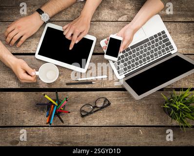 Kollaborativer Arbeitsbereich mit digitalen Geräten und Schreibwaren auf Holztisch während eines produktiven Meetings Stockfoto