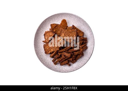 Knusprige hausgemachte Brotcracker oder Croutons mit Samen und Körnern, Salz, Gewürzen und Kräutern auf weißem Hintergrund Stockfoto