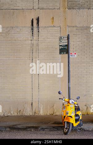 Gelber Roller parkt an einer beigen Ziegelmauer Stockfoto