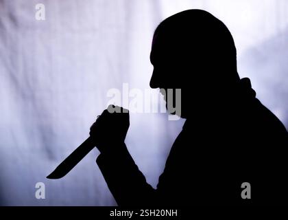 Schatten einer bedrohlichen Silhouette mit Messer 10.02.25, Selters: Symbolfoto, Illustrationsbild, Symbolbild, Illustrationsfoto, Alltagsszene Schatten einer bedrohlichen Silhouette mit Messer dramatische Darstellung einer silhouettierten Person, die ein Messer in der erhobenen Hand halten. Die Szene spielt in einem Innenraum mit unscharfem Hintergrund, was eine bedrohliche und emotionale Atmosphäre schafft. Ideal für Themen wie Kriminalität, Gefahr oder Spannung. . Selters Hessen Deutschland *** Schatten einer bedrohlichen Silhouette mit Messer 10 02 25, Selters Symbol Foto, Illustrationsbild, Sym Stockfoto