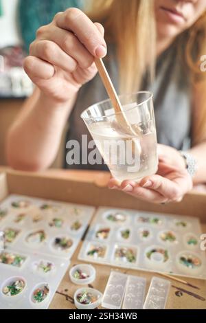 Erwachsene Weibchen, die Harzformen mit Holzstab in Studio-Umgebung basteln. Stockfoto