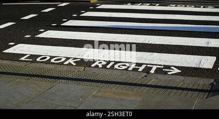 Gemaltes britisches Straßenschild mit Informationen, um direkt auf die Fußgängerüberquerung zu schauen Stockfoto