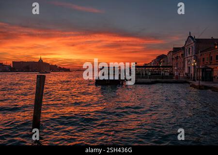 Rotes Blut Himmel Sonnenuntergang über der Lagune von Venedig mit Salute Basilika Kuppeln und alte Lampen Stockfoto