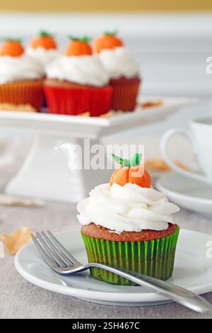 Kürbis-Gewürz-Cupcakes mit Vanille-Zuckerglasur und mit Kürbisauflagen verziert. Stockfoto
