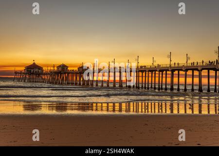 Huntington Beach Pier in Kalifornien während eines wunderschönen Sonnenuntergangs, der durch Rauch eines nahegelegenen Waldfeuers hervorgehoben wird. Stockfoto