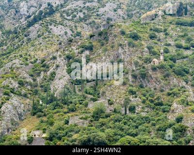 Kotor, Montenegro - 2. Juli 2024: Kirche unserer Lieben Frau von Remedy auf dem hohen grauen Berghang über der historischen Altstadt. Befestigte Mauer und Pfad bedeuten Stockfoto