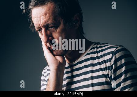 Bedauernswerter Mann mit Hand im Gesicht, leises Porträt eines traurigen, verzweifelten kaukasiers in Bedauern, selektiver Fokus Stockfoto