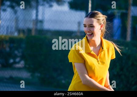 Tennisspielerin lächelt, während sie an einem sonnigen Tag Tennis spielt Stockfoto