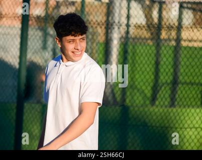 Glücklicher Tennisspieler, der während des Trainings an einem sonnigen Tag lächelt und wegblickt Stockfoto