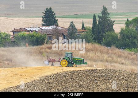 Traktor pflügt im Sommer in der Toskana, Italien, Europa, ein getrocknetes Getreidefeld in einer typischen toskanischen Landschaft auf Kreta Senesi Stockfoto