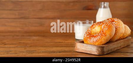 Leckere Bagels und Milch auf hölzernem Hintergrund mit Platz für Text Stockfoto
