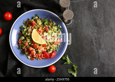 Teller mit köstlichem Tabbouleh-Salat auf dunklem Hintergrund Stockfoto