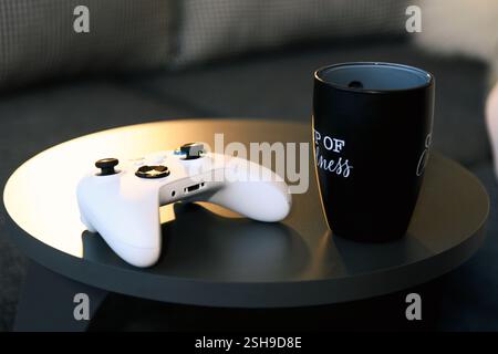 Izmir, Türkei - 9. Februar 2025: Ein Foto eines weißen Xbox-Gaming-Controllers, der auf einem Tisch neben einer Kaffeetasse platziert wird, um ein gemütliches und modernes Gaming zu schaffen Stockfoto