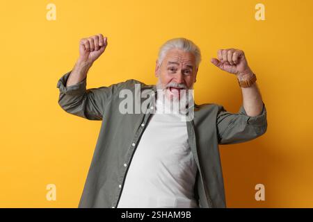 Porträt eines emotionalen älteren Mannes auf orangefarbenem Hintergrund Stockfoto