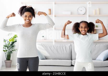 Starke afroamerikanische Mutter und Tochter zeigen ihre Muskeln Stockfoto