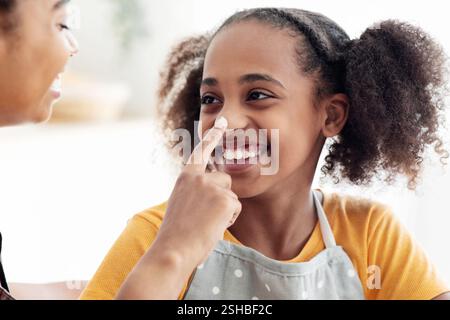 Nahaufnahme einer schwarzen Dame, die ihre Töchternase mit Mehl befleckt hat Stockfoto