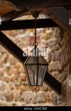 Hängende Laterne unter Holzbalken mit Steinmauerhintergrund Stockfoto