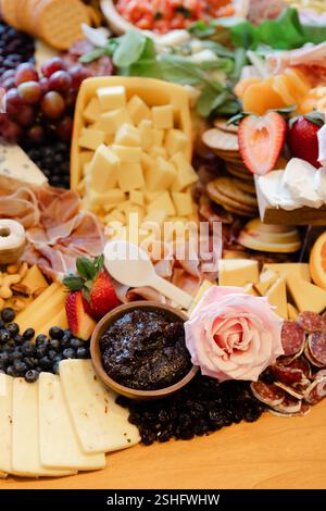 Eine schön angeordnete Käseplatte bietet verschiedene Käsesorten, Früchte, Nüsse und Aufstriche, perfekt für ein Treffen. Stockfoto
