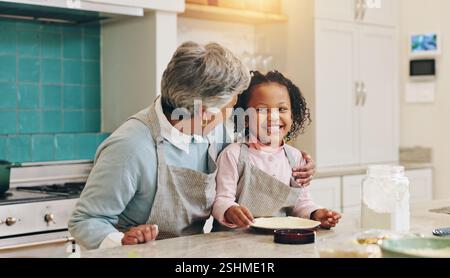 Großmutter, Kind und Umarmung zum Backen zu Hause, Unterrichten von Fähigkeiten und Gebäck für Kuchen in der Küche. Familie, Umarmung und Mädchen lernen Rezept für Dessert Stockfoto