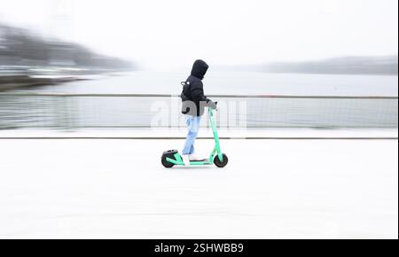 Hannover, Deutschland. Februar 2025. Ein Mann fährt einen E-Roller über das schneebedeckte Nordufer des Maschsees. Quelle: Julian Stratenschulte/dpa/Alamy Live News Stockfoto